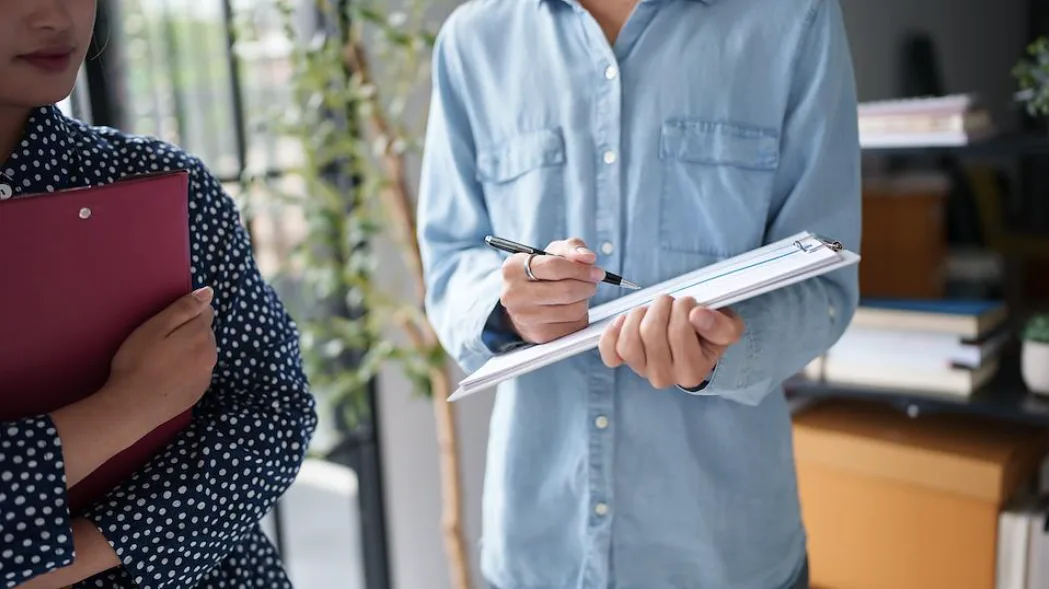 Two colleagues reviewing documents on clipboards